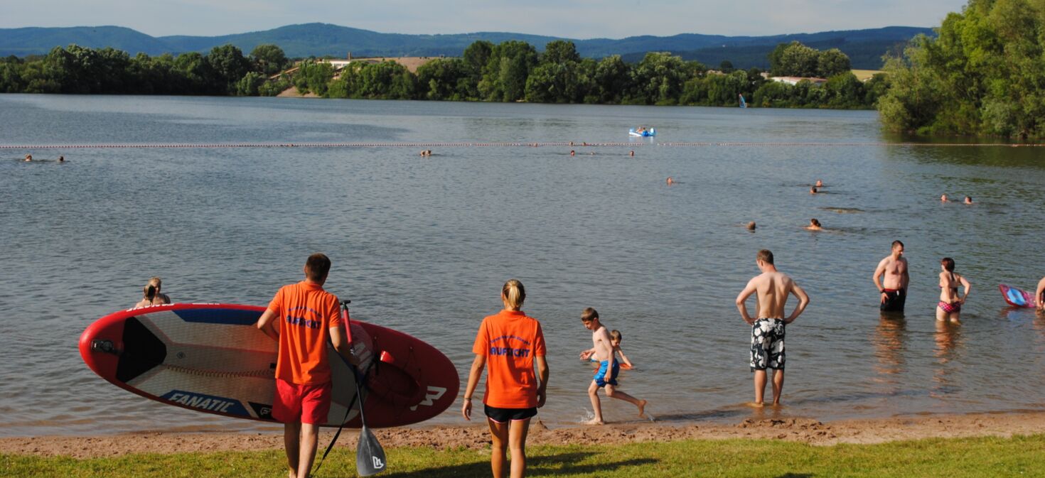 Landschaftsaufnahme Strandbad Breitungen mit Blick auf den Badesee und Menschen