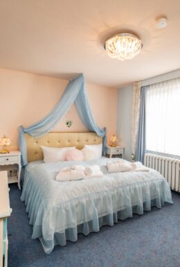 Innenaufnahme Zimmer mit Bett, Kommode und Schreibtisch mit TV