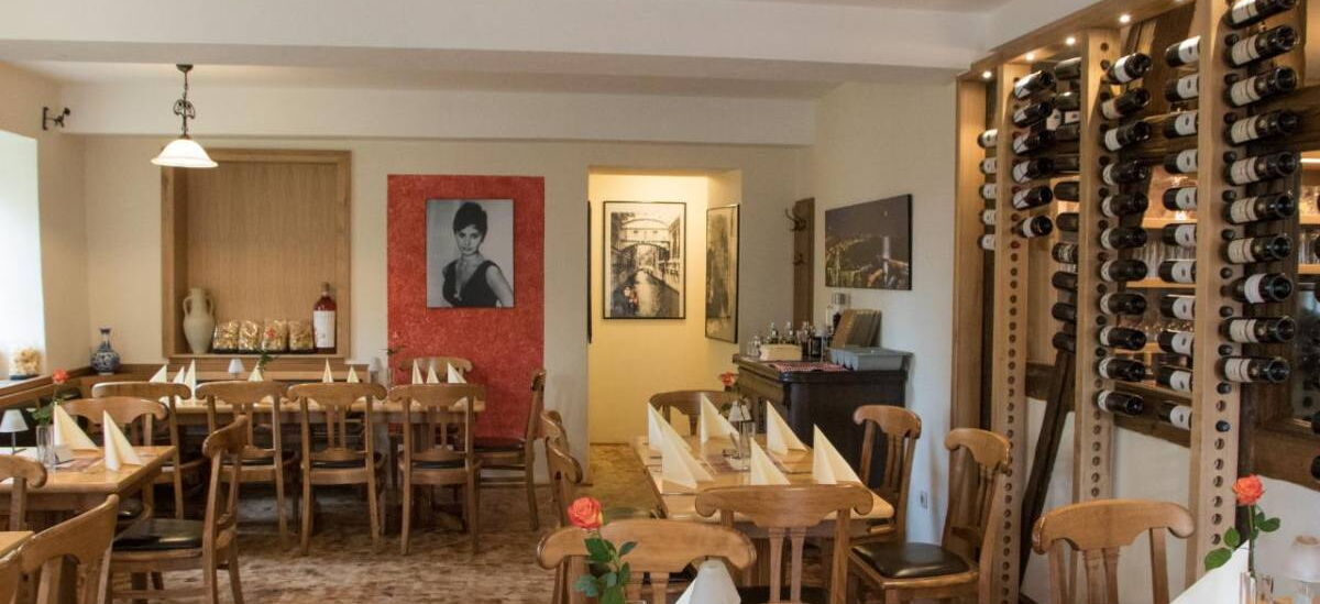 Innenaufnahme Gastraum Ristorante Esposito mit Esstischen und rustikalem Weinregal