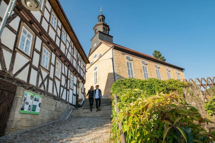 Wanderpaar an der Barockkirche Steinbach und dem Heimatstübchen
