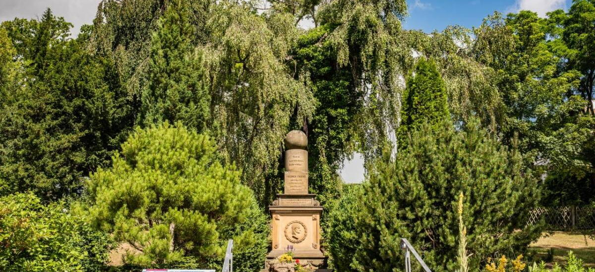 Fröbelgrab Friedhof Schweina mit Portrait von Friedrich Fröbel und den Spielgaben Kugel, Walze und Würfel